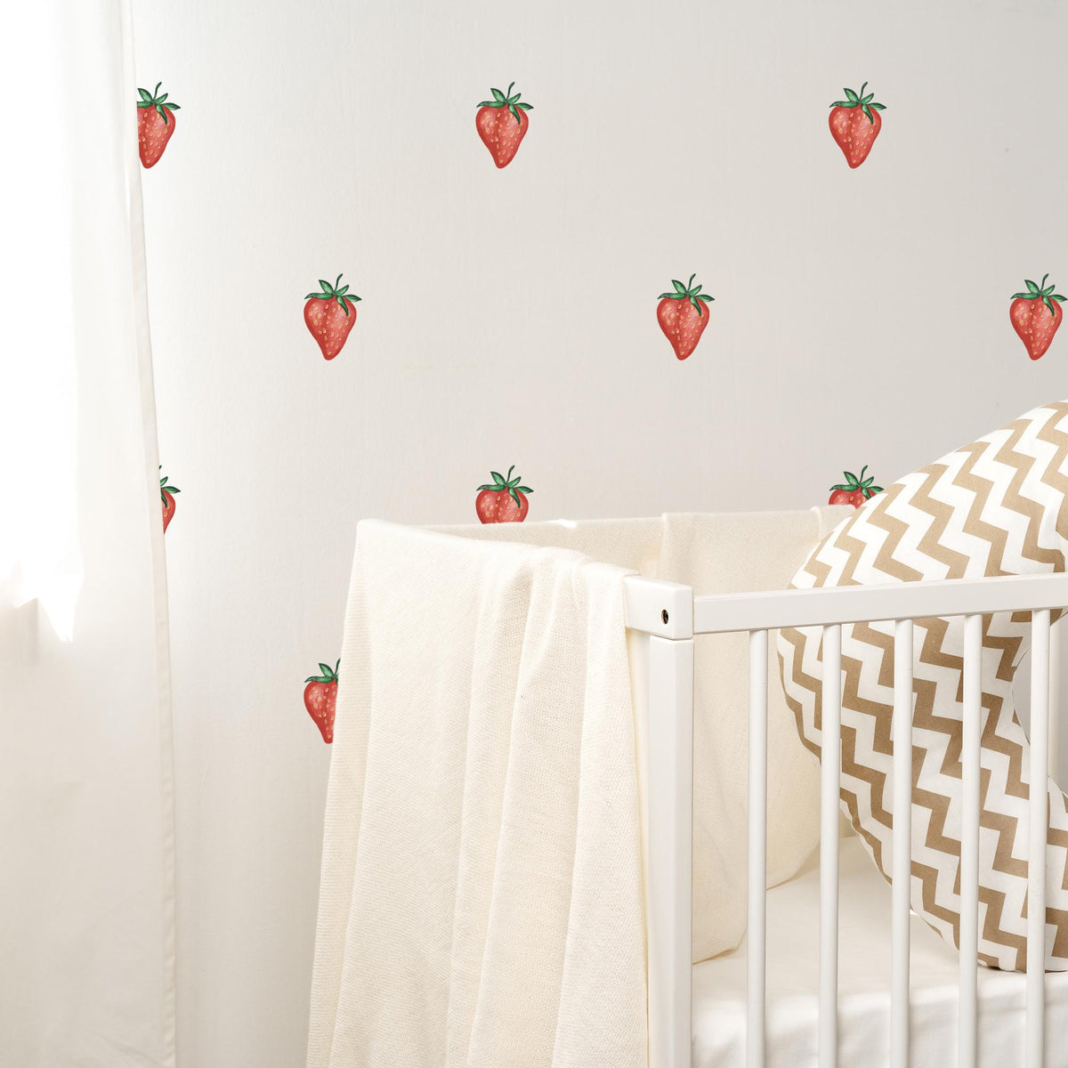 Crib with strawberry wall decals in a nursery setting